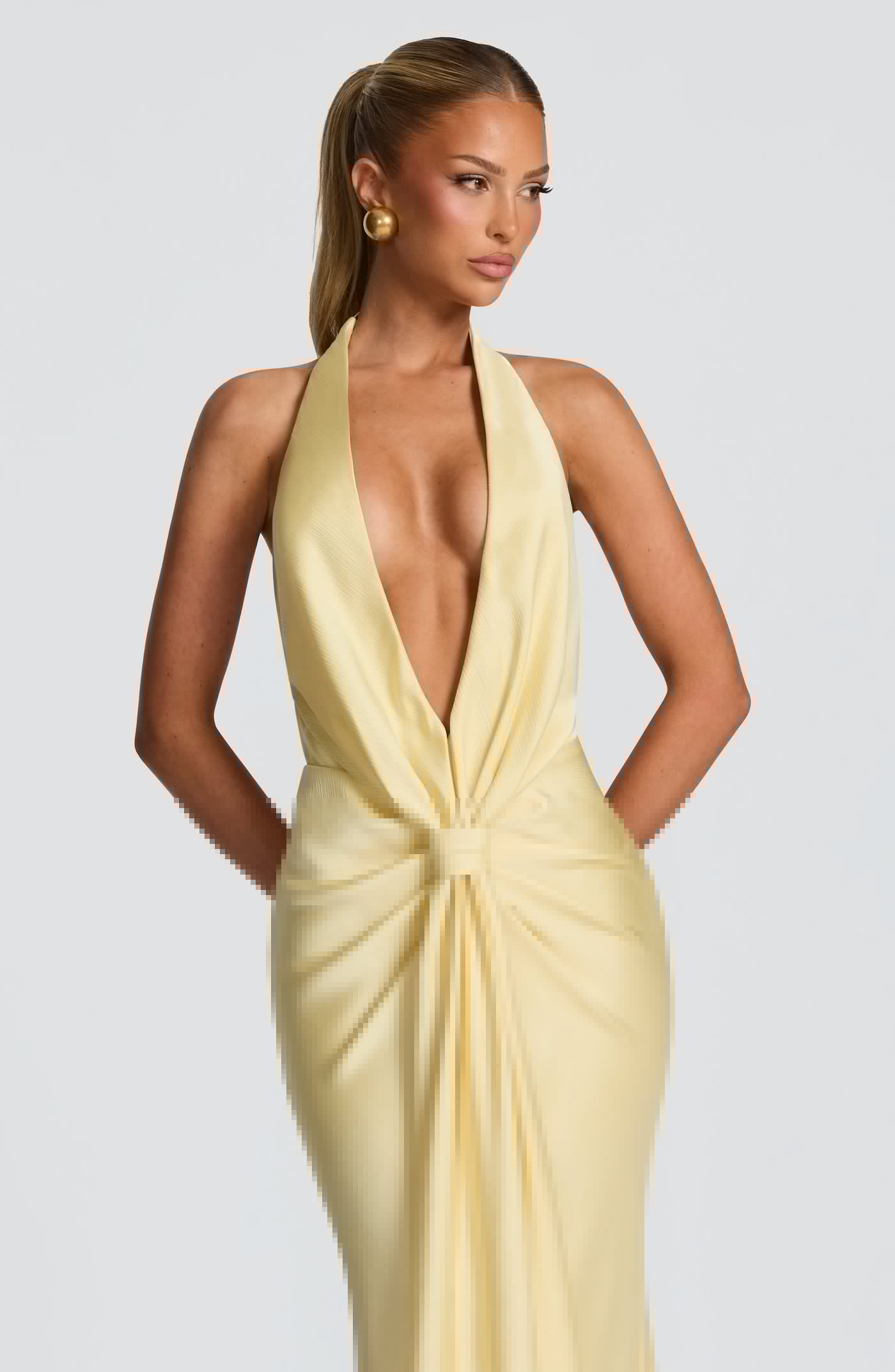 Woman wearing a yellow evening gown with a plunging neckline on a plain background