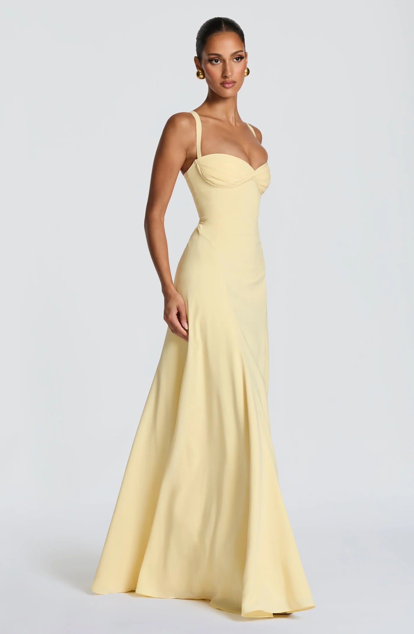 Side profile of the Sura Maxi Dress featuring the draped hip panel and flowing full skirt with godet details for elegant movement